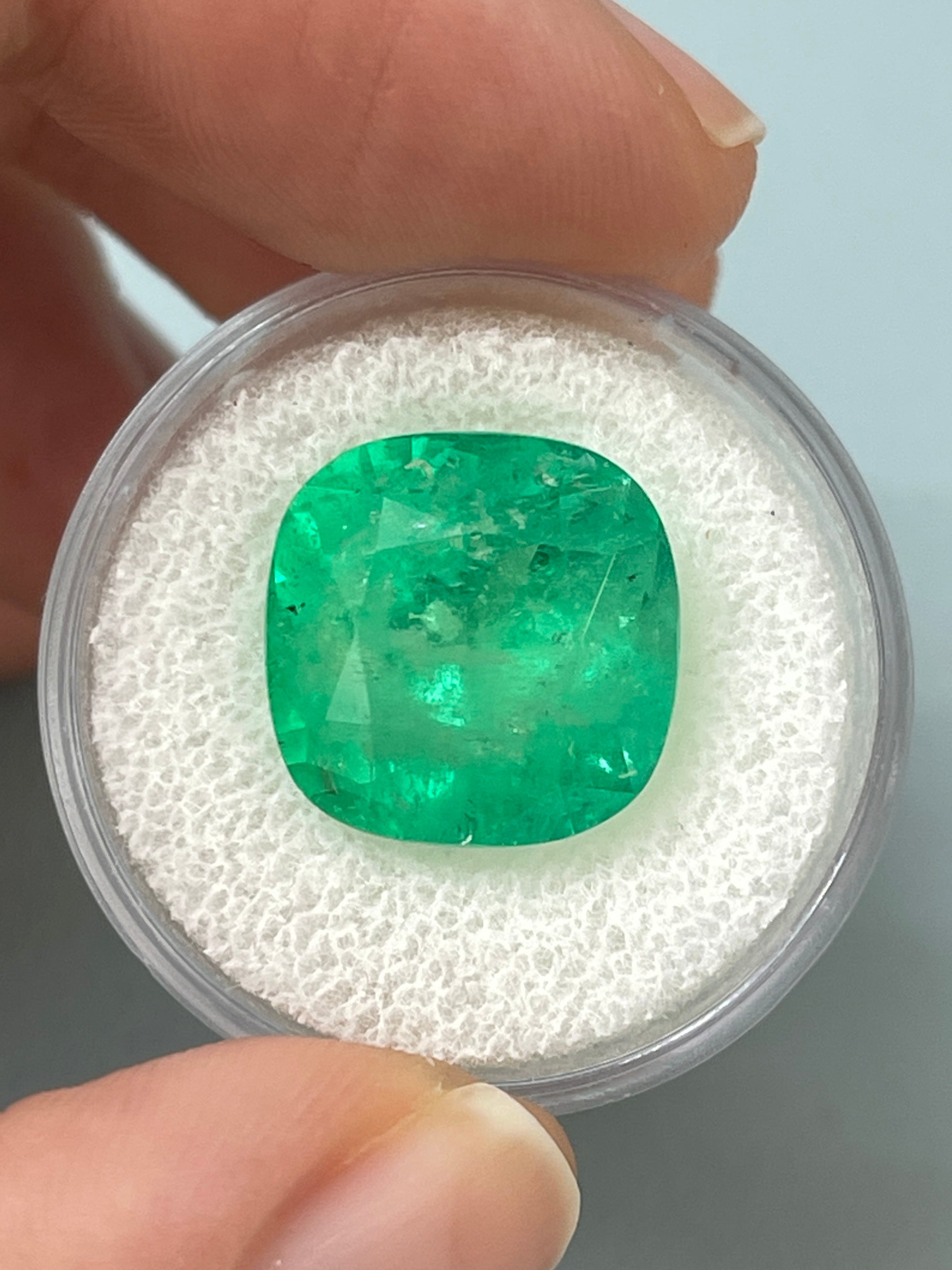 Large 12.66 carat natural Colombian emerald in a 14x14 cushion cut, showcasing vibrant green color and clarity.