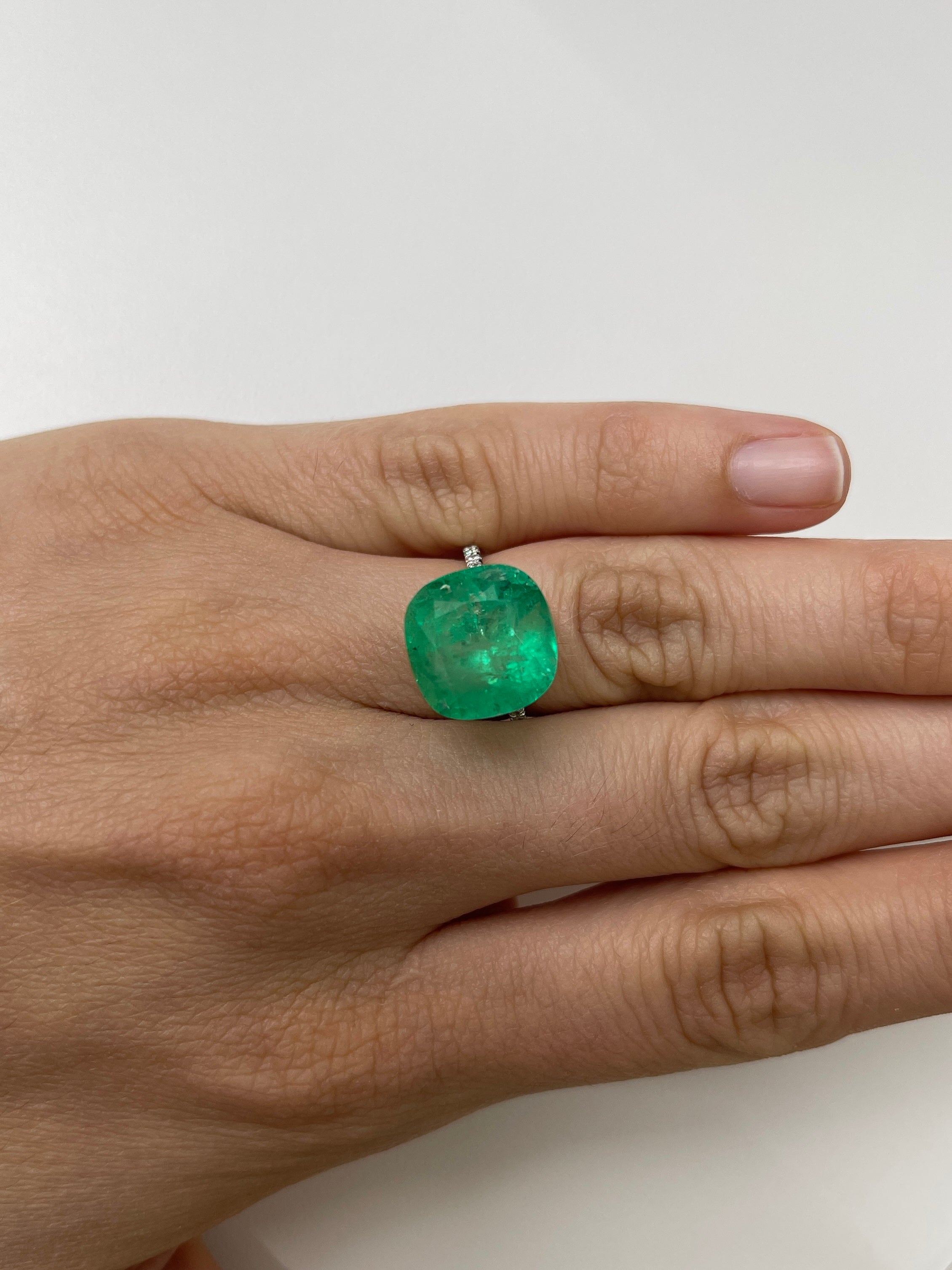 Large 12.66 carat natural cushion-cut Colombian emerald from JR Colombian Emeralds, showcasing vibrant green color and clarity.