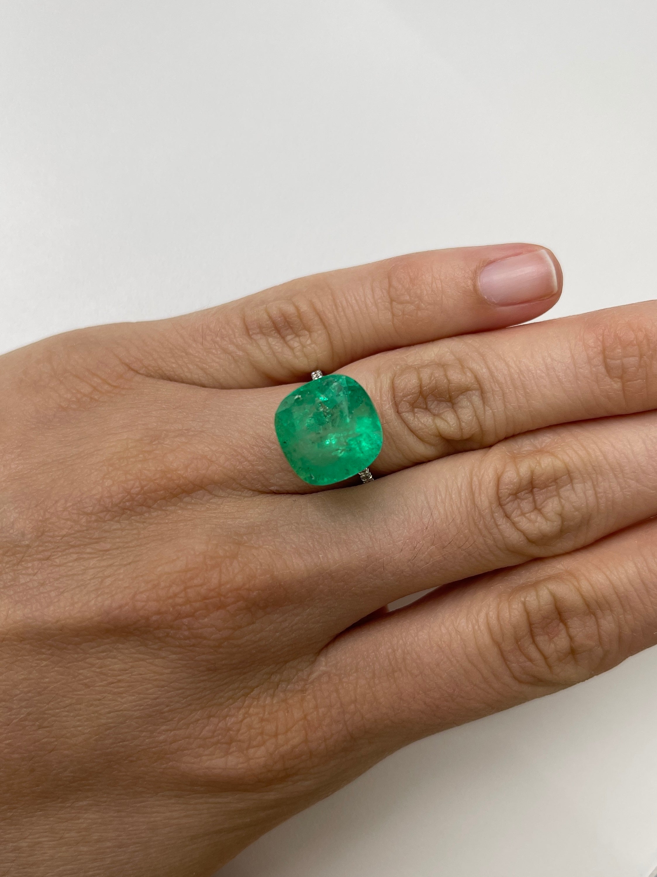 Large 12.66-carat natural Colombian emerald in 14x14 cushion cut, showcasing vibrant green color and clarity.