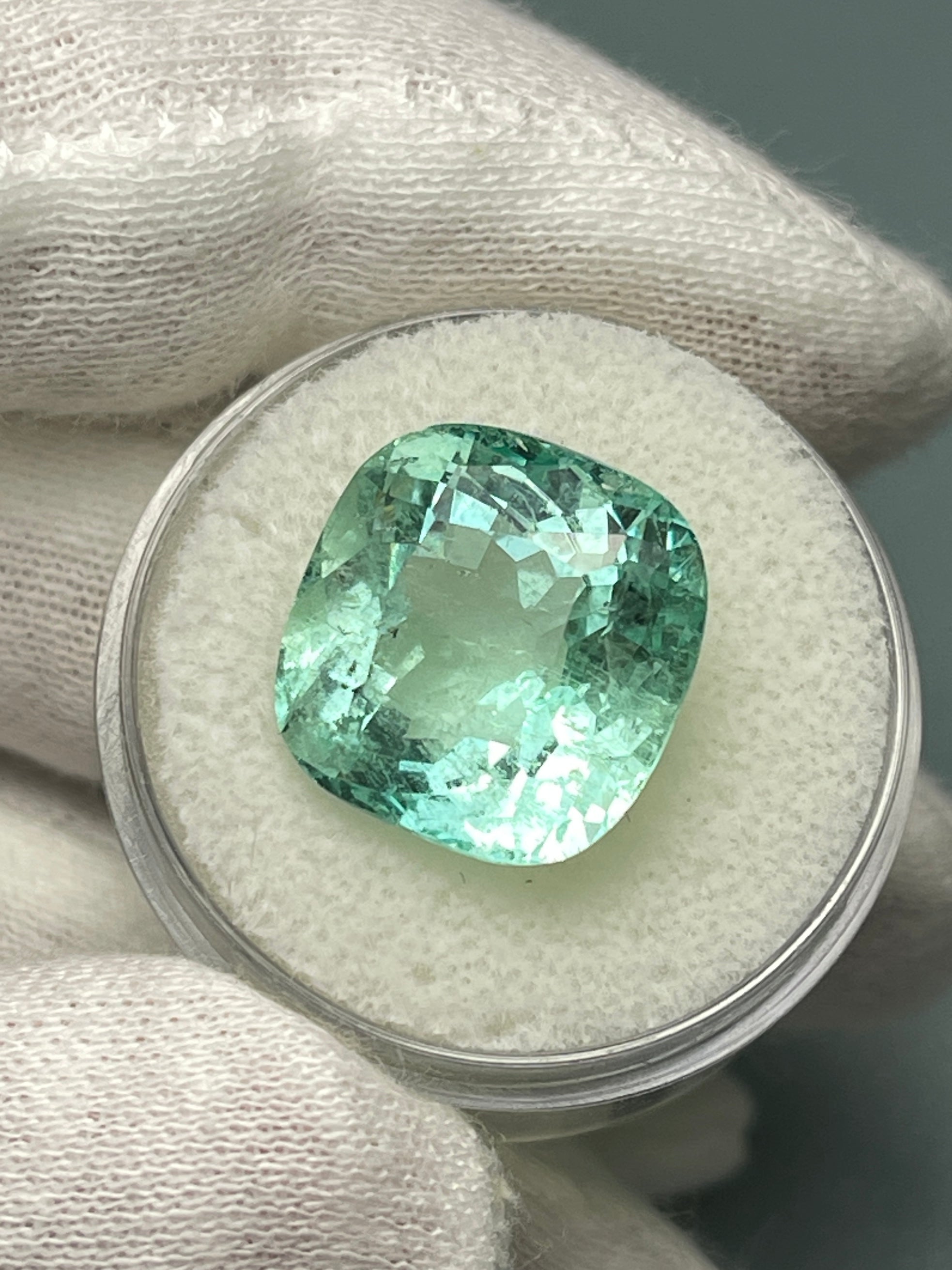 Large 12.86 carat natural cushion-cut Colombian emerald from JR Colombian Emeralds, showing deep green color and faceted surface.