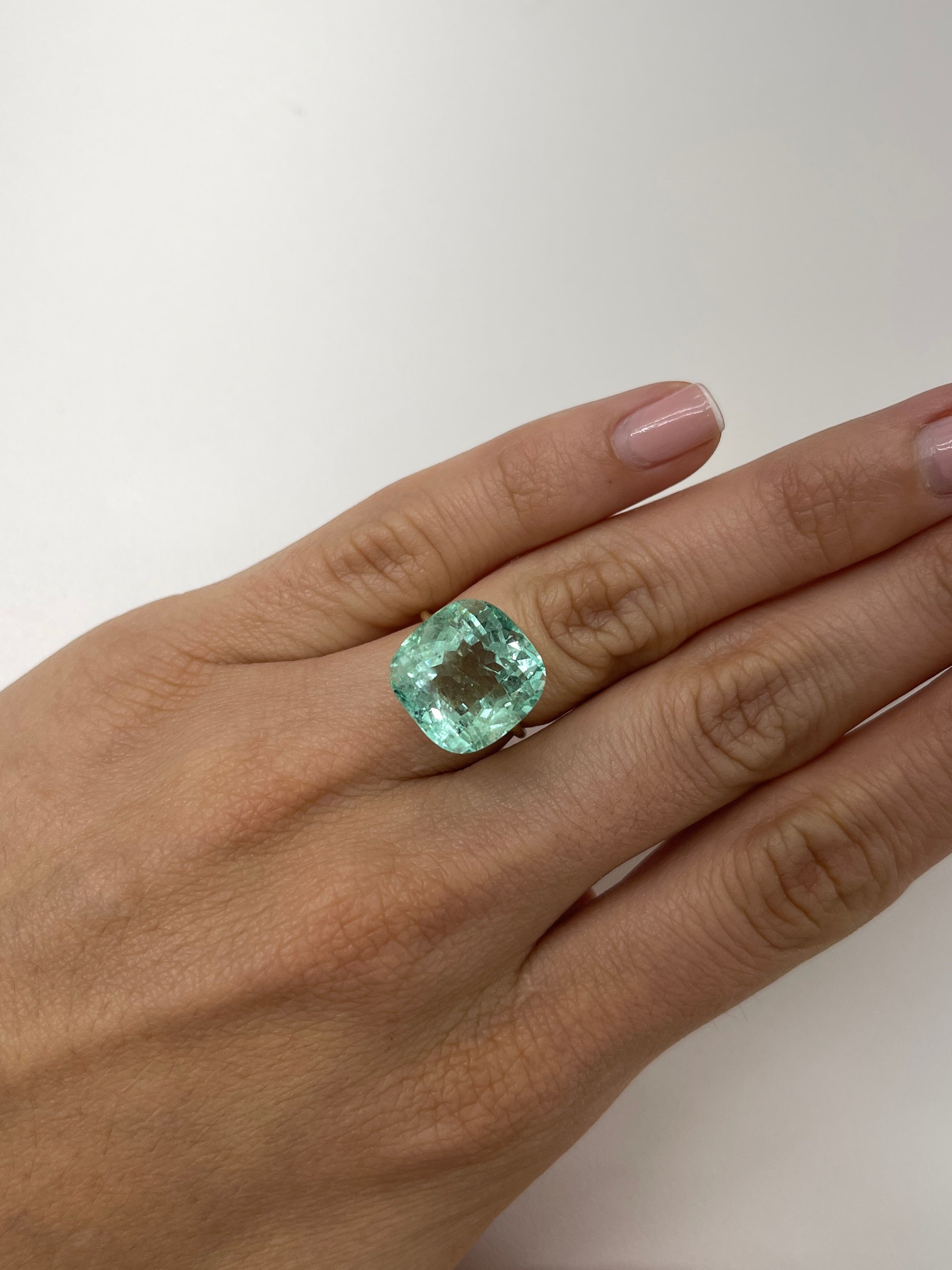 Large 12.86 carat natural cushion-cut Colombian emerald from JR Colombian Emeralds with vibrant green color.