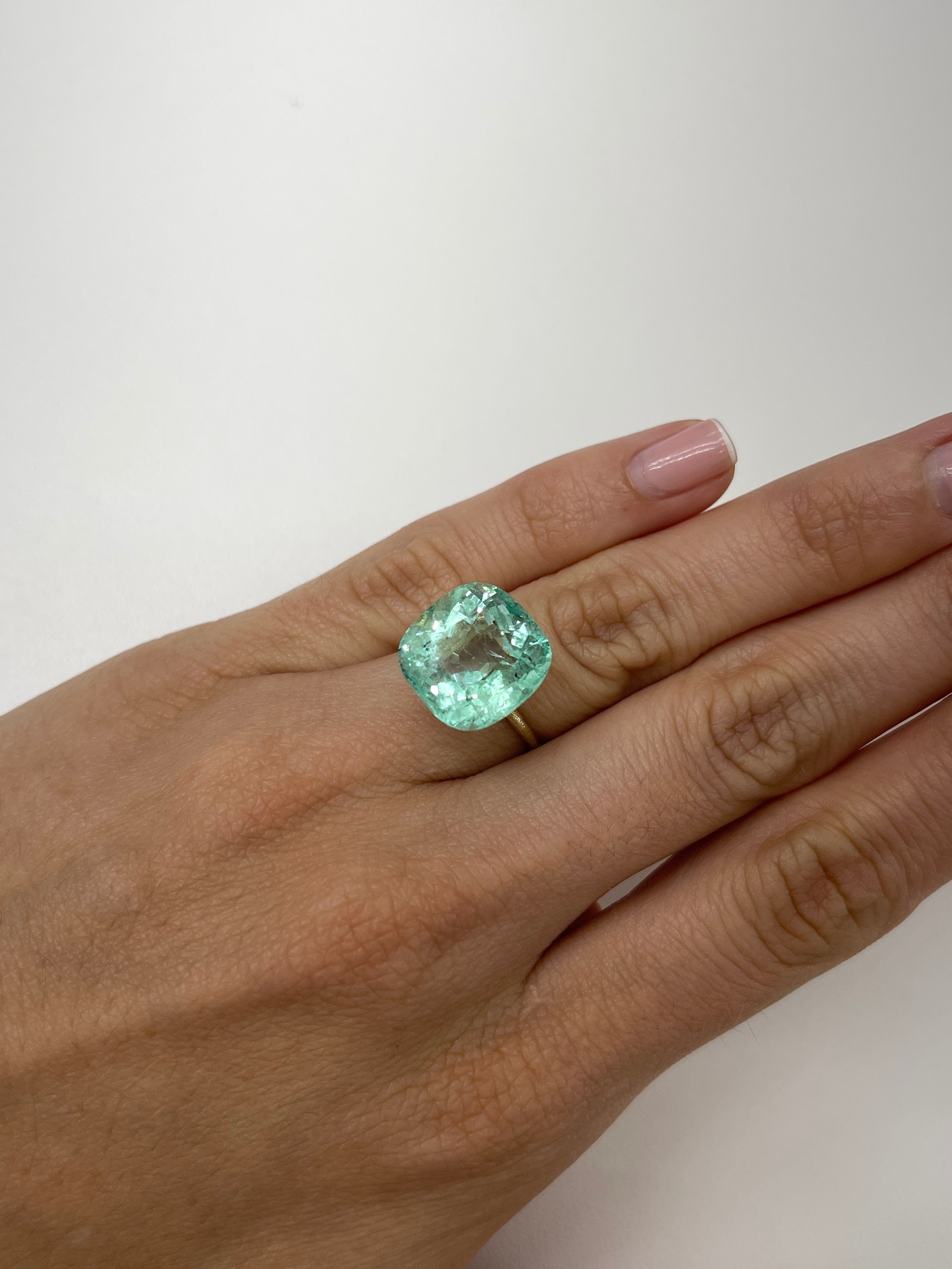 Large 12.86 carat natural cushion-cut Colombian emerald from JR Colombian Emeralds, showcasing vibrant green color and clarity.