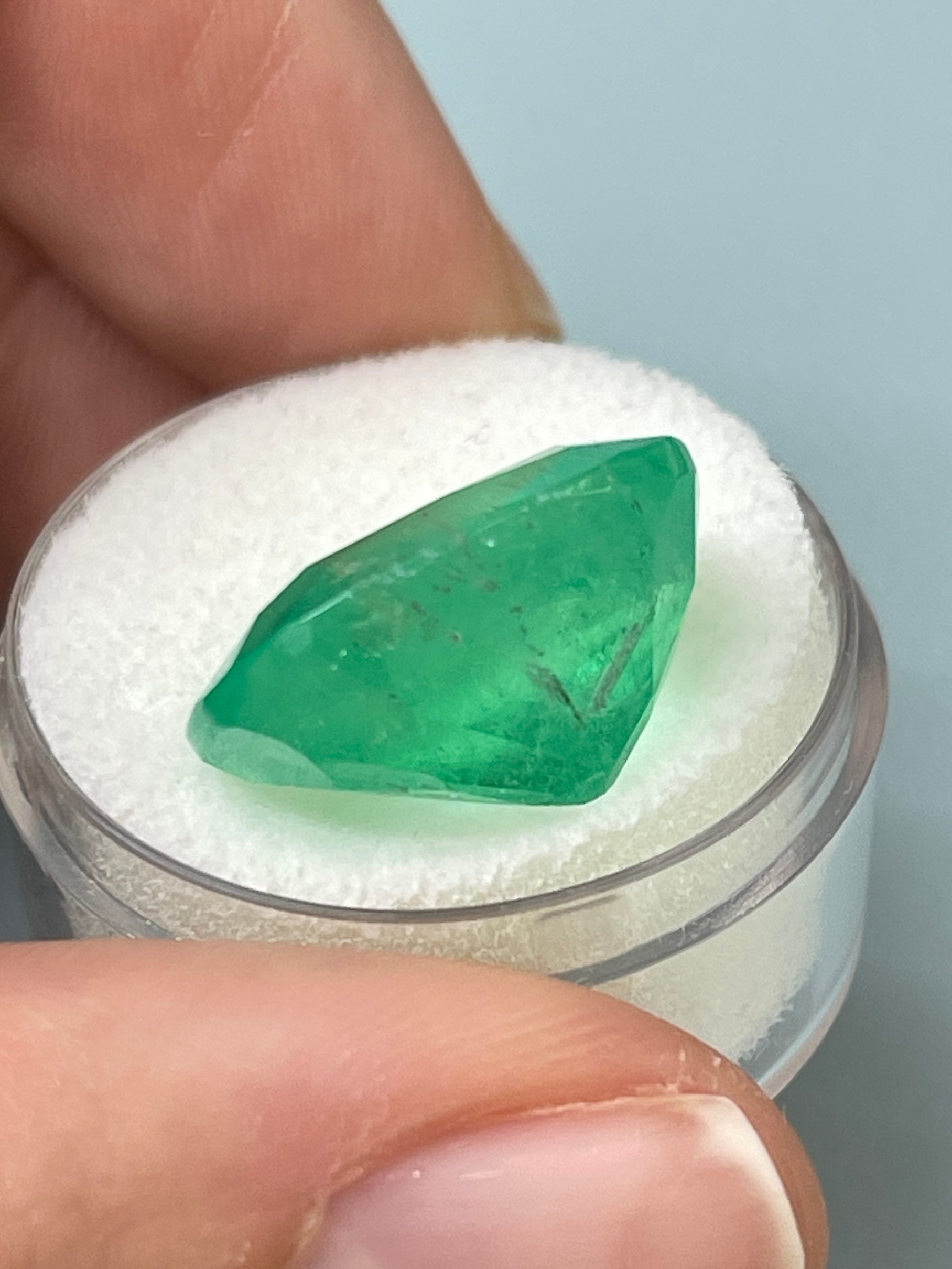Large 17.5x15 Colombian Emerald cushion cut gemstone from JR Colombian Emeralds, showcasing a vibrant natural green hue and smooth facets.