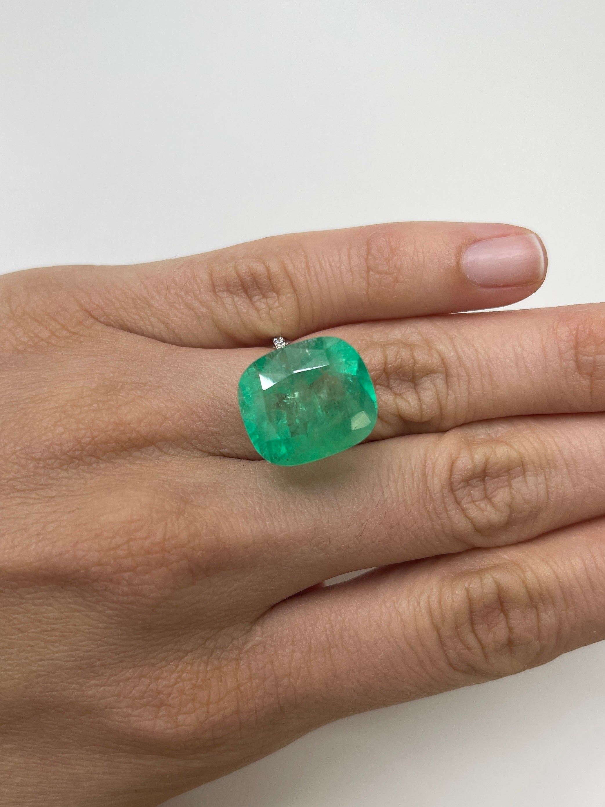 Large 17.5x15 Colombian Emerald cushion cut gemstone from JR Colombian Emeralds, showcasing vibrant green color and natural clarity.