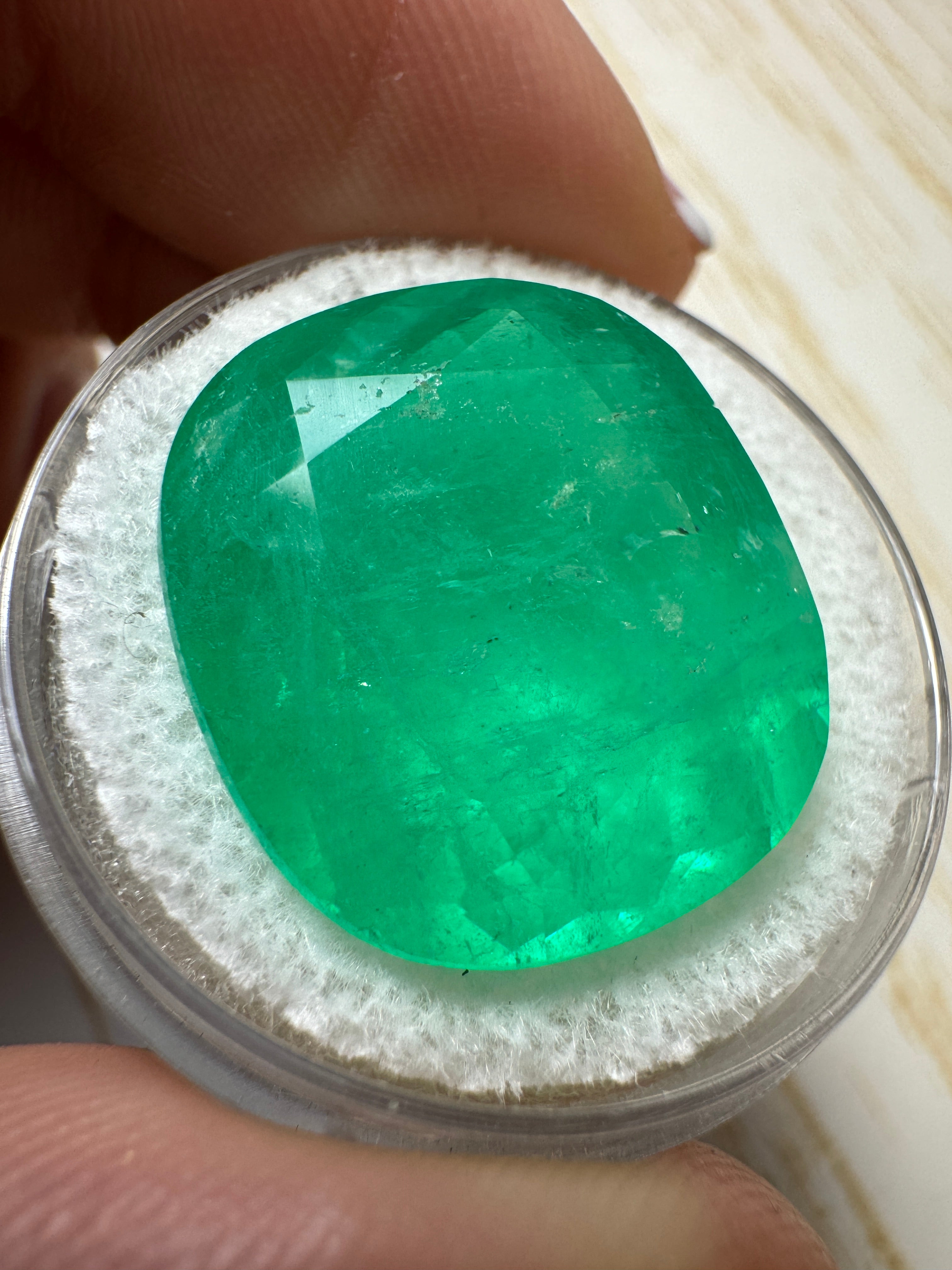 Large 19.63-carat natural Colombian emerald loose cushion cut gemstone with vibrant green color and chunky appearance.