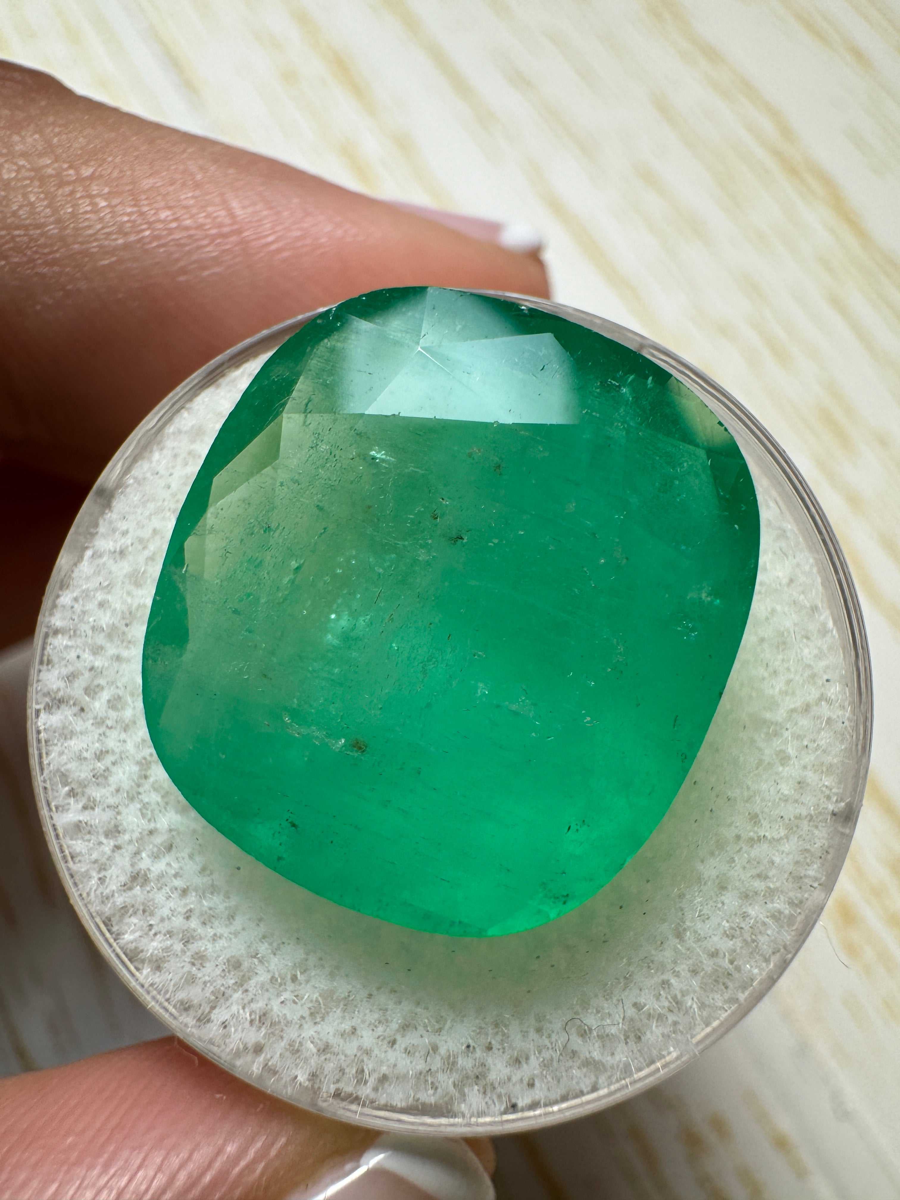 Large 21.62 Carat earthy green natural Colombian emerald loose cushion cut gemstone, showcasing vibrant color and clarity.