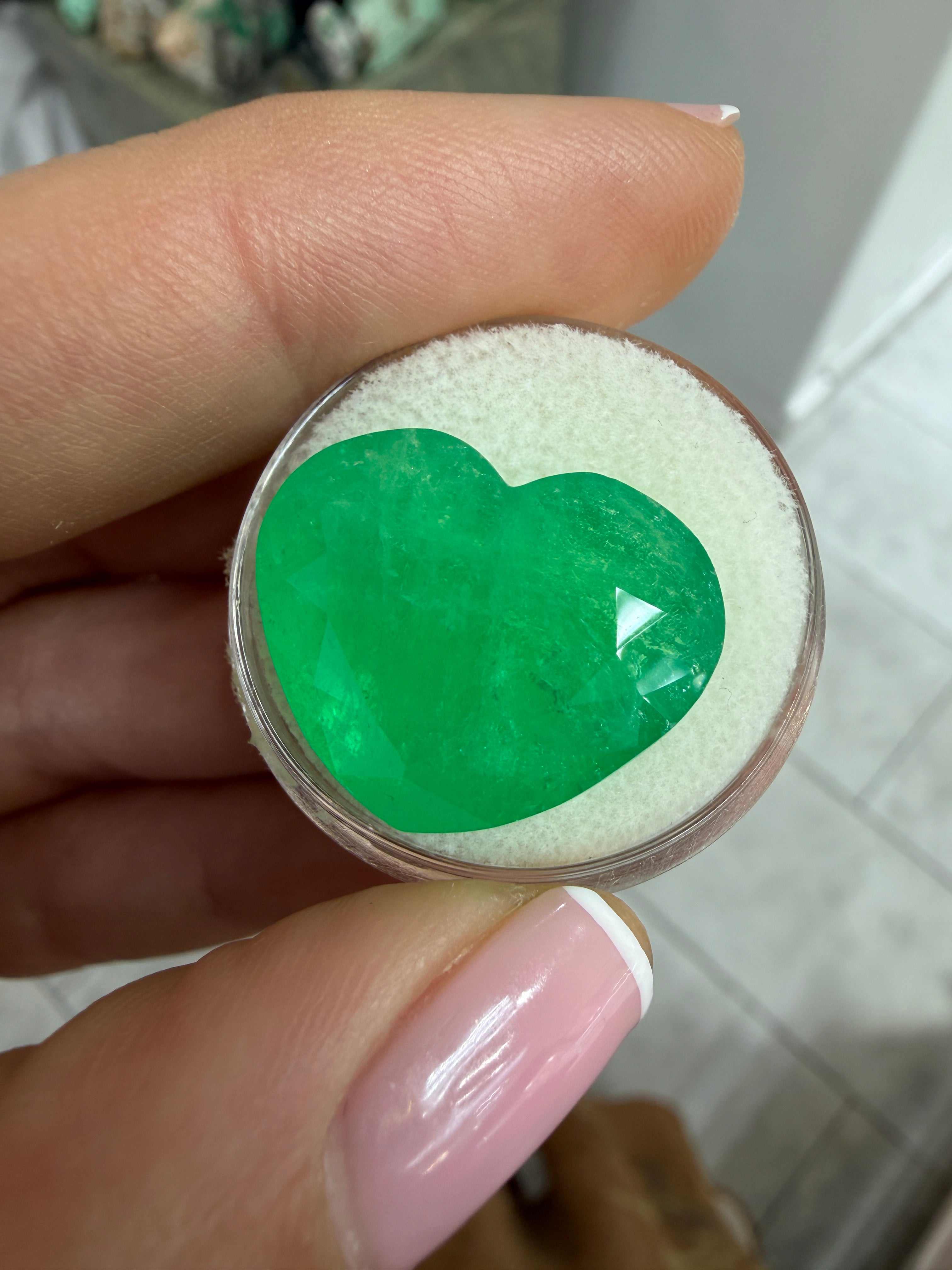 Bright green 23.97-carat natural Colombian emerald loose heart cut gemstone, showcasing vibrant color and clarity.