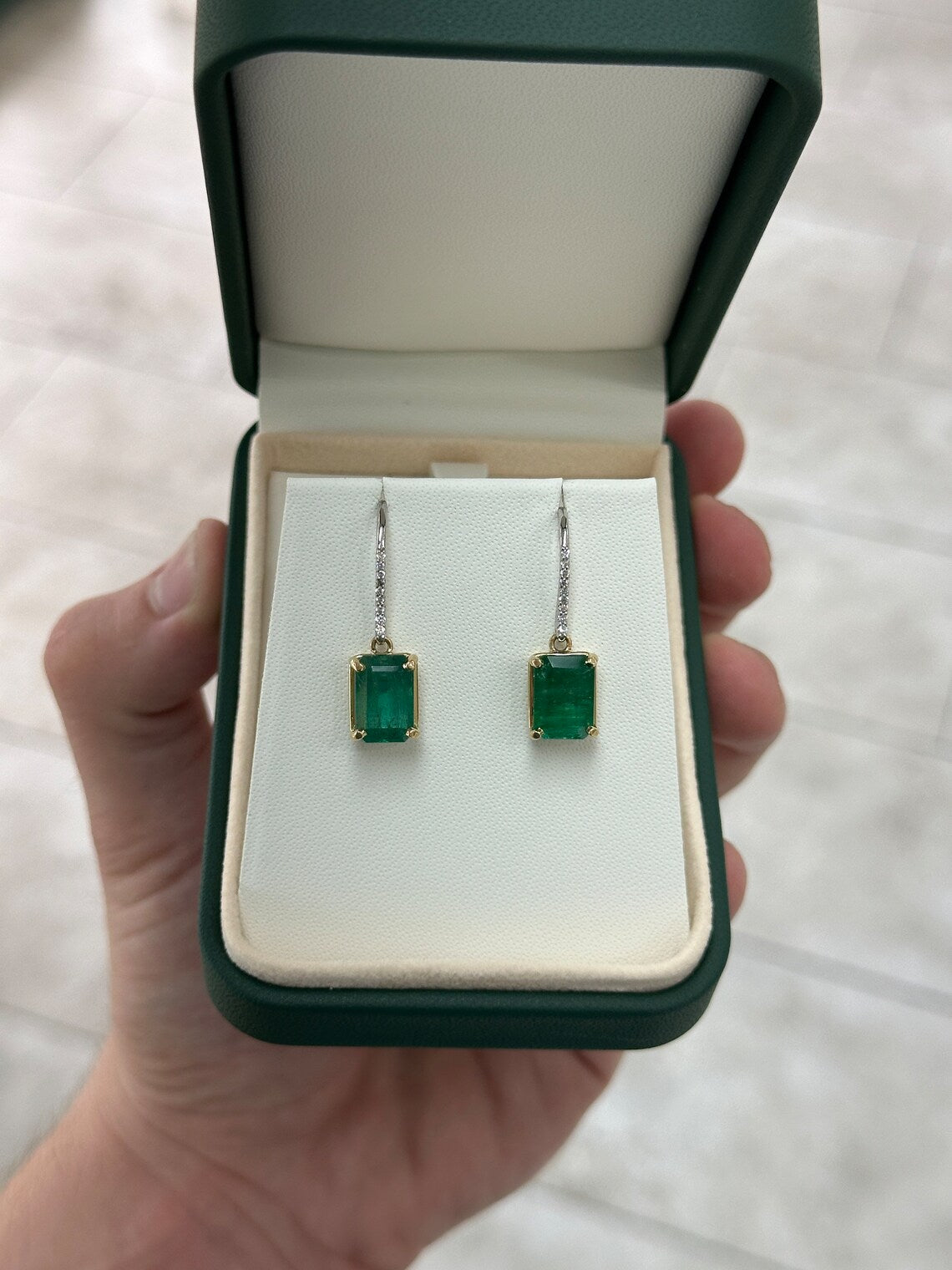 JR Colombian Emeralds earrings with 8.32tcw emerald dangle features, diamonds, and leverback hooks on a white background.