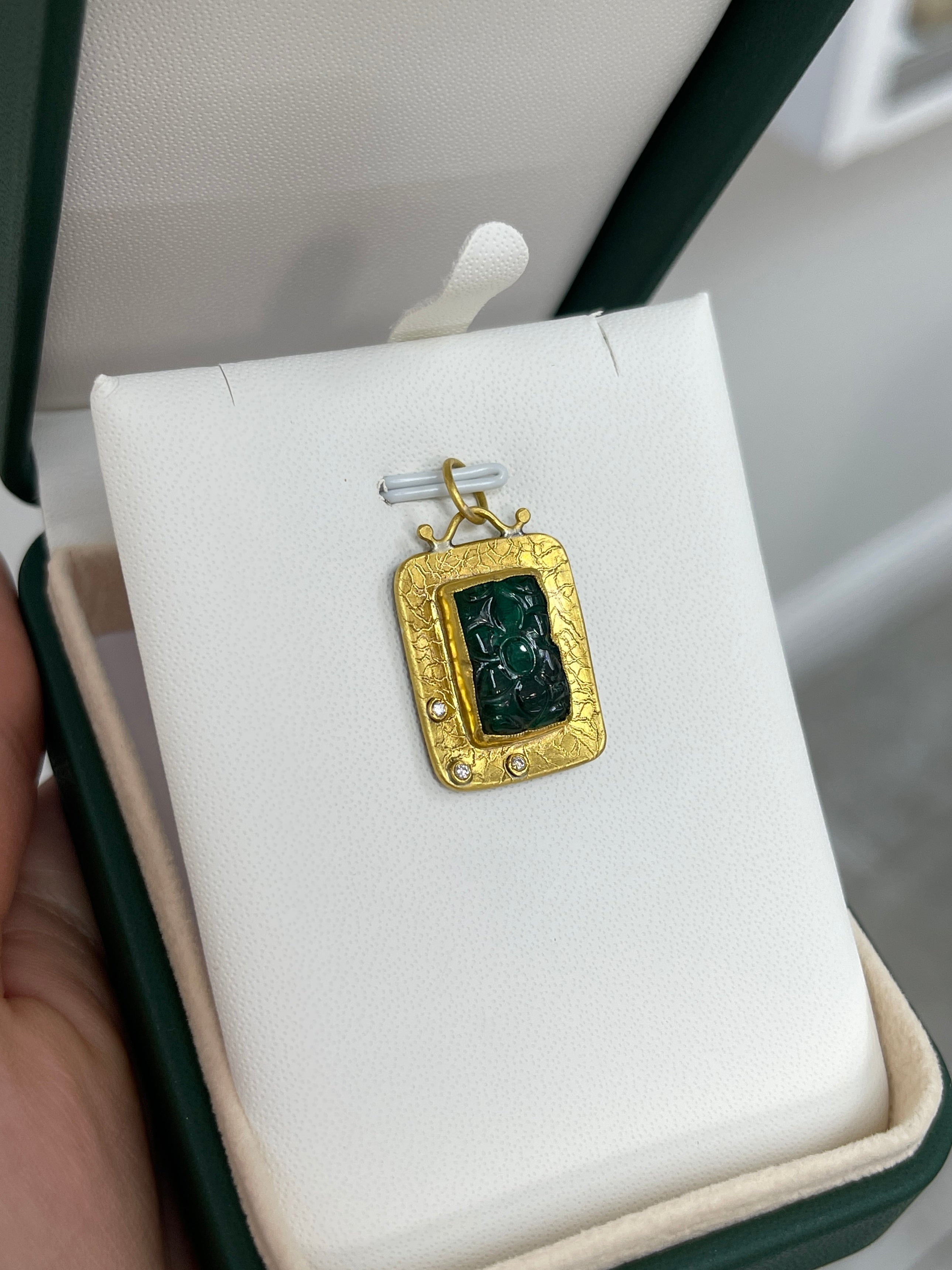 Floral hand-carved emerald and diamond pendant in 24K gold, featuring intricate details and vibrant green stones.