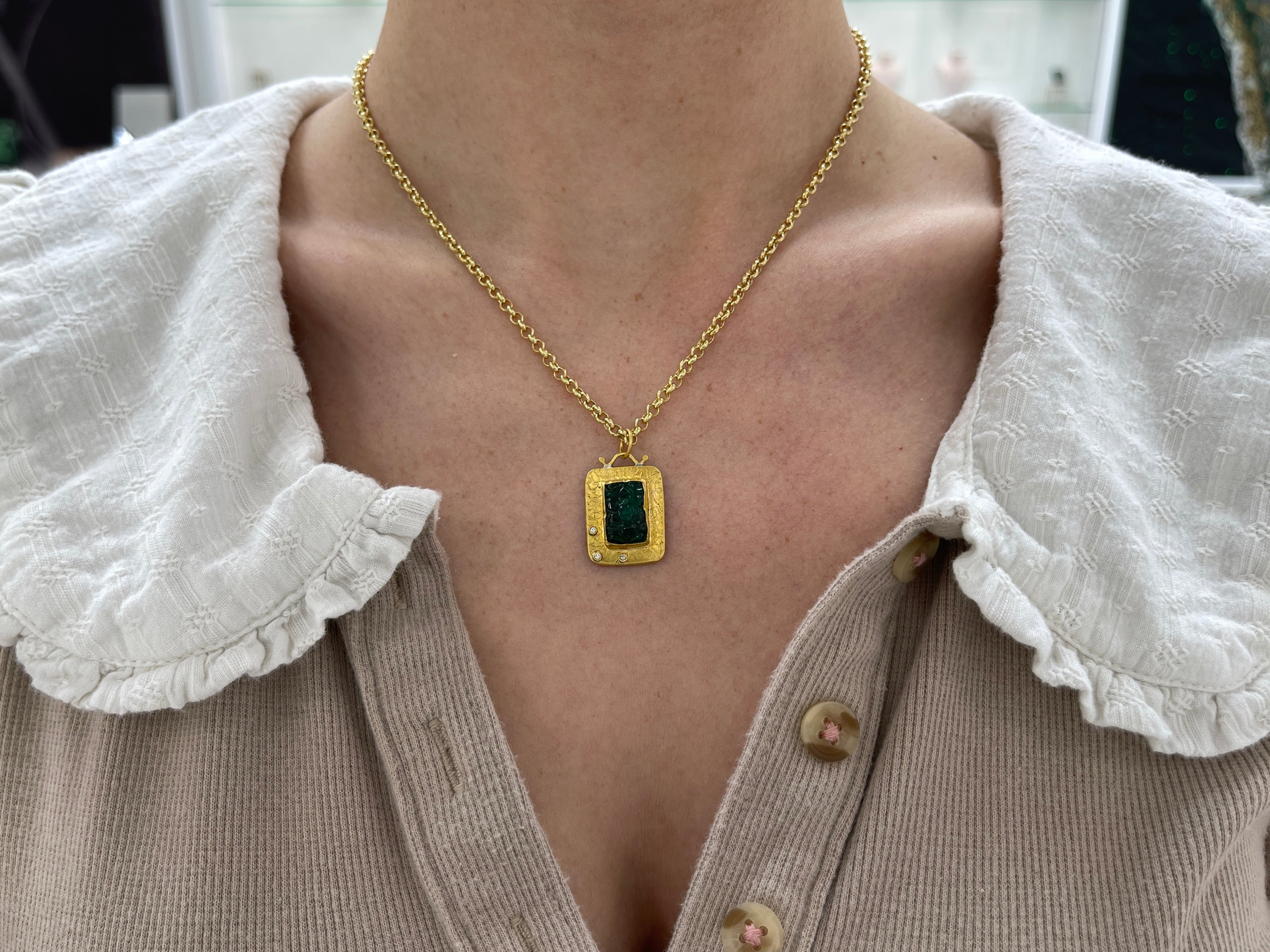 Floral hand-carved emerald and diamond pendant in 24K gold, showcasing intricate design and vibrant green hues.