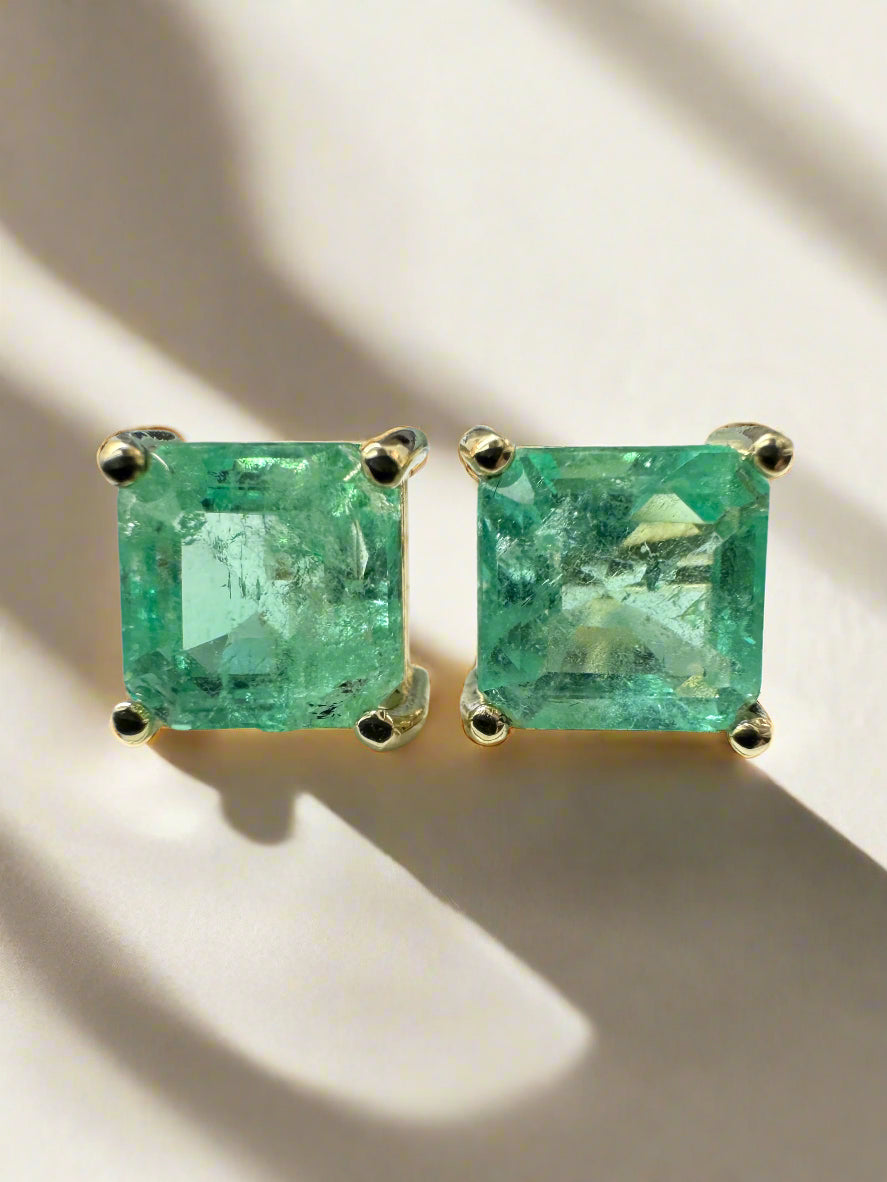 Asscher cut Colombian emerald stud earrings with 3.97 total carats in 14K setting, featuring earthy spring green hues.
