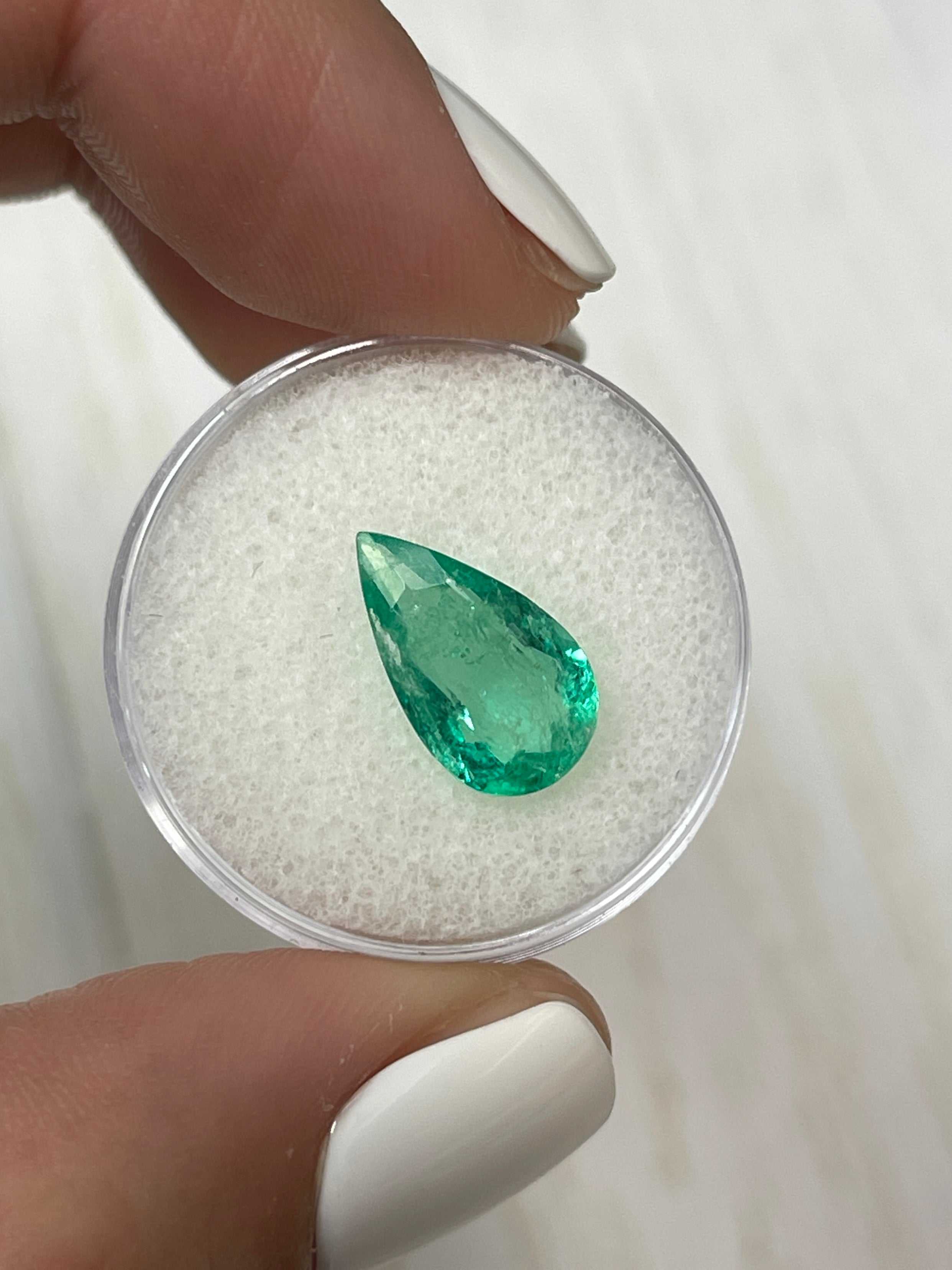 Natural 2.61 carat Colombian emerald loose gemstone with pear cut and green color, displayed on a white background.