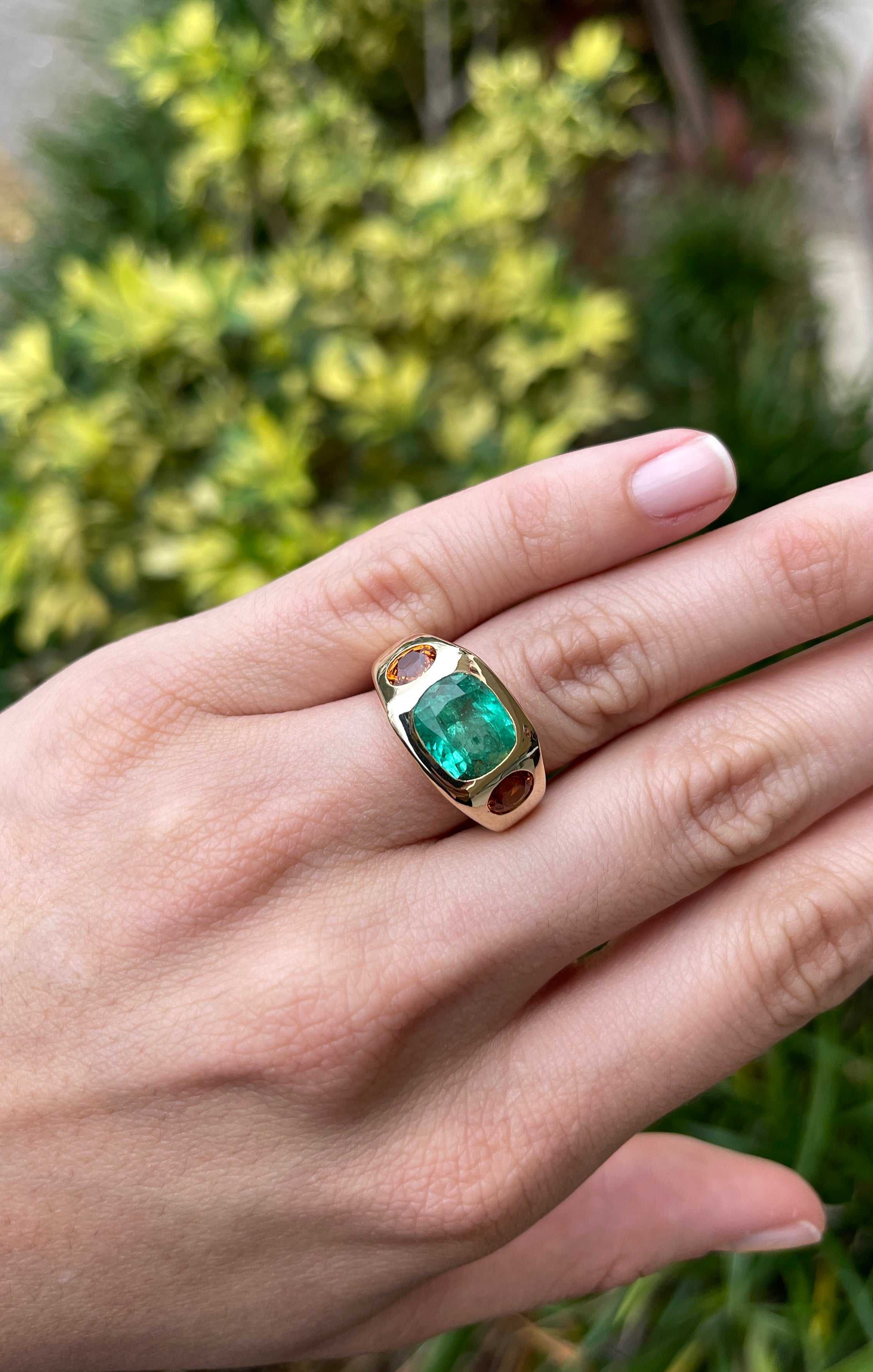 7 carat three stone natural cushion cut emerald and oval sapphire gypsy gold ring on hand 14k