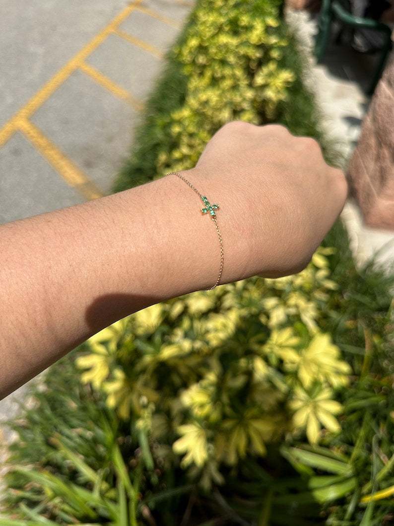 14K gold emerald cross bracelet with 0.20tcw round cut vivid medium green natural Colombian emeralds.