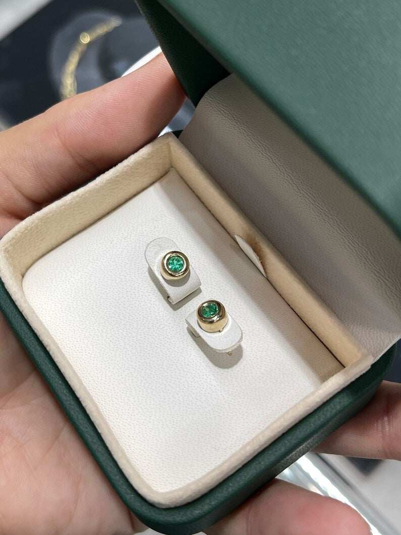 Yellow gold Colombian Emerald earrings with round cut bezel-set spring green emeralds, 0.50 carats total weight.