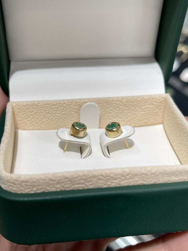 Colombian Emerald 0.50ctw round cut bezel set earrings in 14K yellow gold, featuring vibrant spring green emeralds.