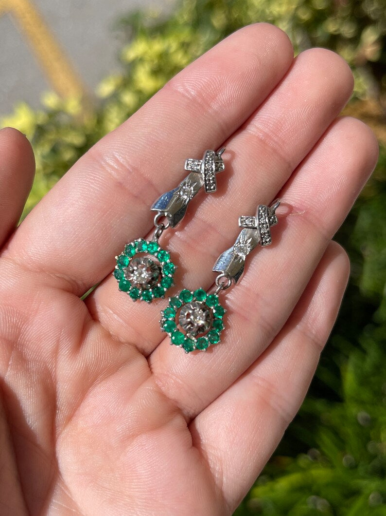 Vintage 14K Colombian Emerald and diamond halo dangle earrings with vivid green round emeralds and intricate metalwork.