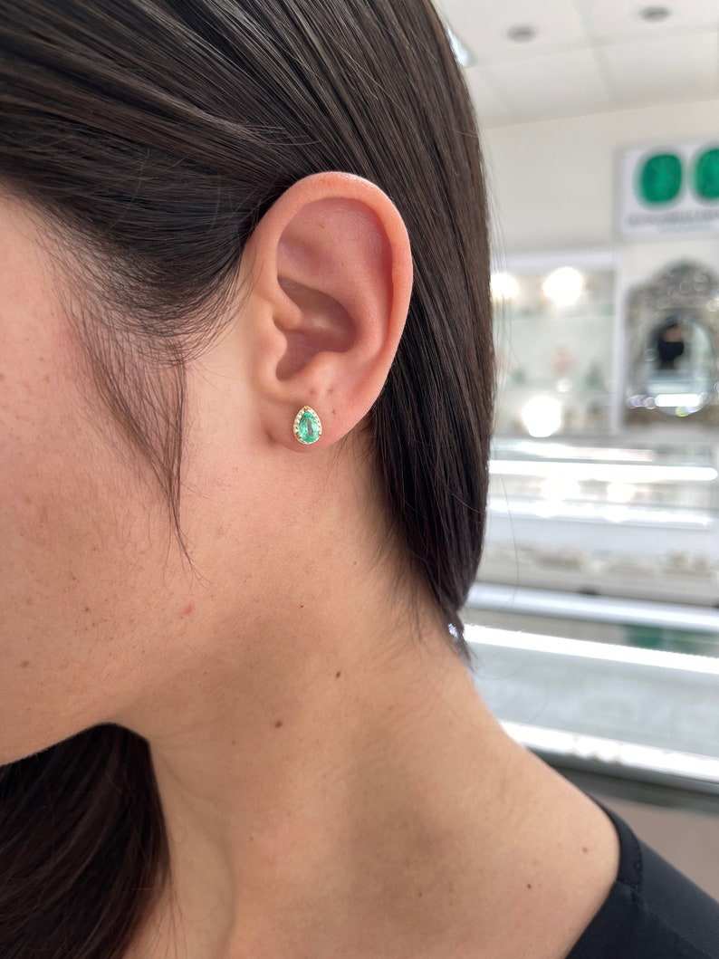 Natural emerald and diamond halo pear cut earrings in 14K gold, featuring Colombian emeralds and sparkling accents.