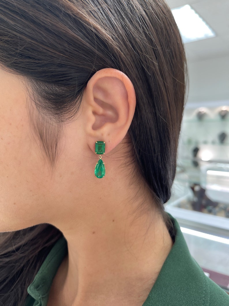 Colombian Emerald 18K gold dangle earrings with dark vivid green emeralds and pear-shaped cut gemstones.