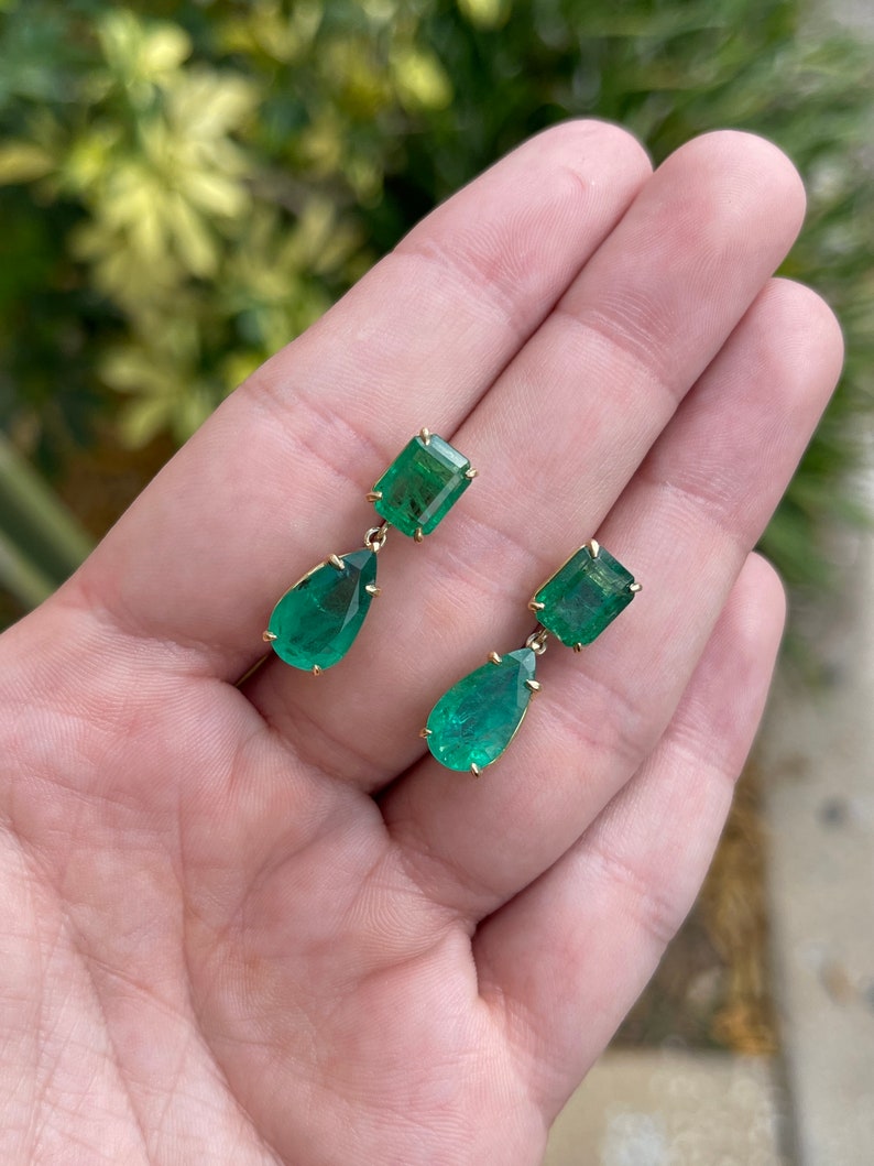 Colombian Emerald earrings featuring 11.26 carats of dark vivid green emeralds with pear-shaped dangles and 18K gold setting.