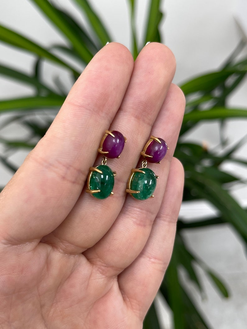 Colombian Emerald and Ruby dangle earrings featuring 13.82 tcw 18K natural emerald cabochons and 6-ray star ruby accents.