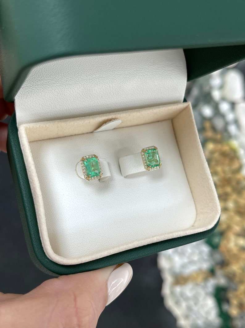 Colombian Emerald earrings featuring 2.10tcw 14K gold with natural 9x7 emerald-cut diamond halo stud design