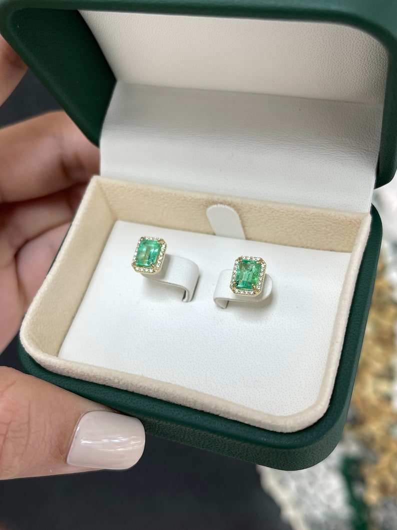 Colombian Emerald earrings featuring 2.10tcw 14K gold with natural 9x7 emerald-cut diamond halo stud design.