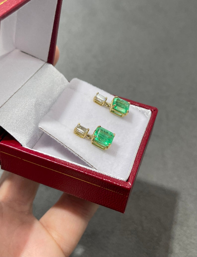 Elongated emerald and diamond dangle earrings in 18K gold, featuring natural transparent Colombian emeralds and sparkling diamonds.