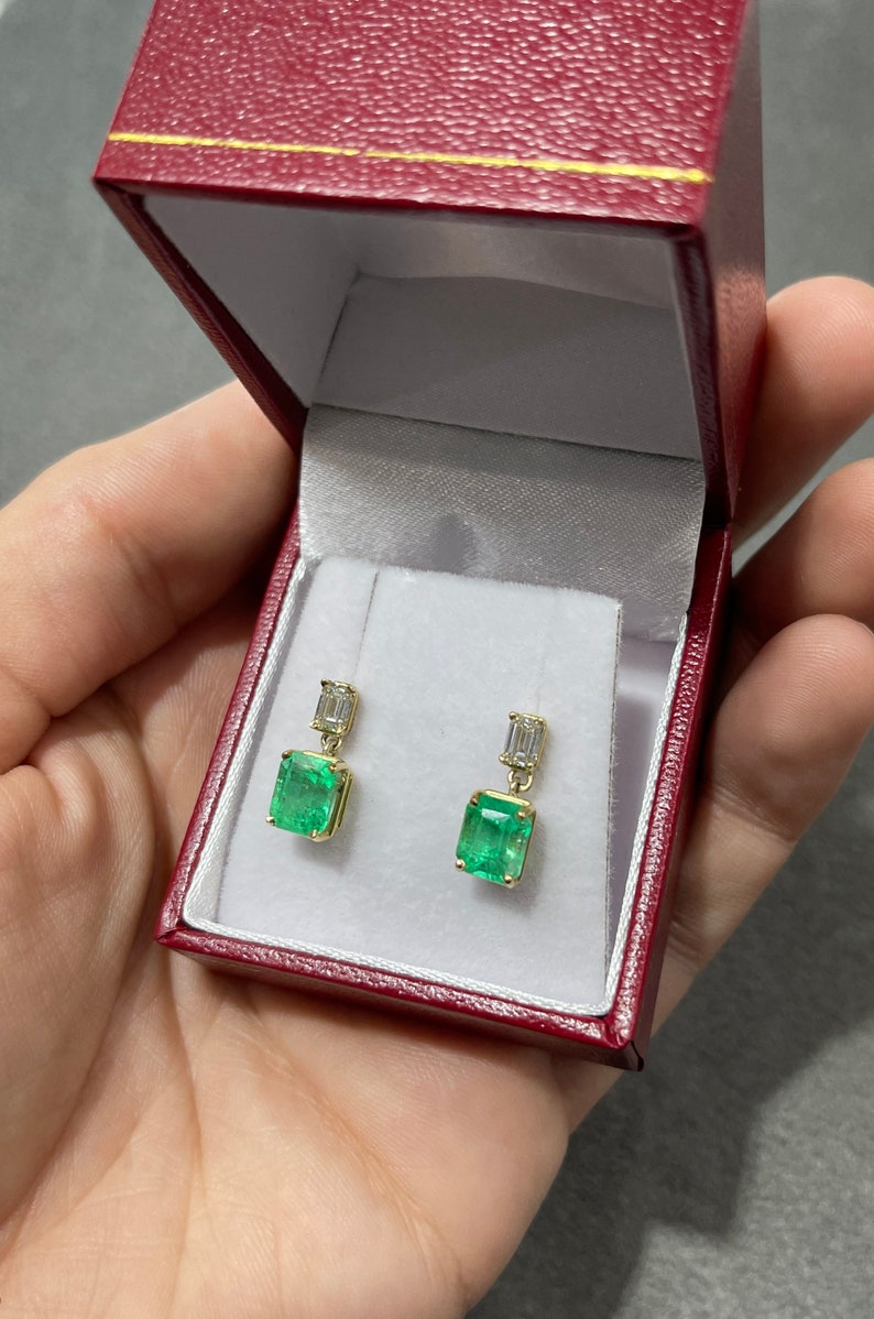Elongated emerald and diamond dangle earrings with 18K gold setting, featuring natural transparent gemstones and Colombian emeralds.