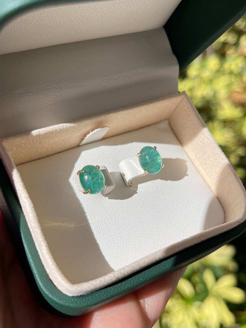 Natural emerald stud earrings featuring oval cut deep bluish green emeralds in 14K gold setting by Colombian Emerald.