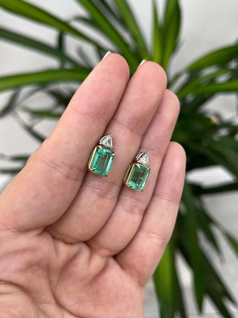 Pair of Colombian Emerald and diamond trillion accent two-stone platinum earrings featuring 6.73 carats total weight.