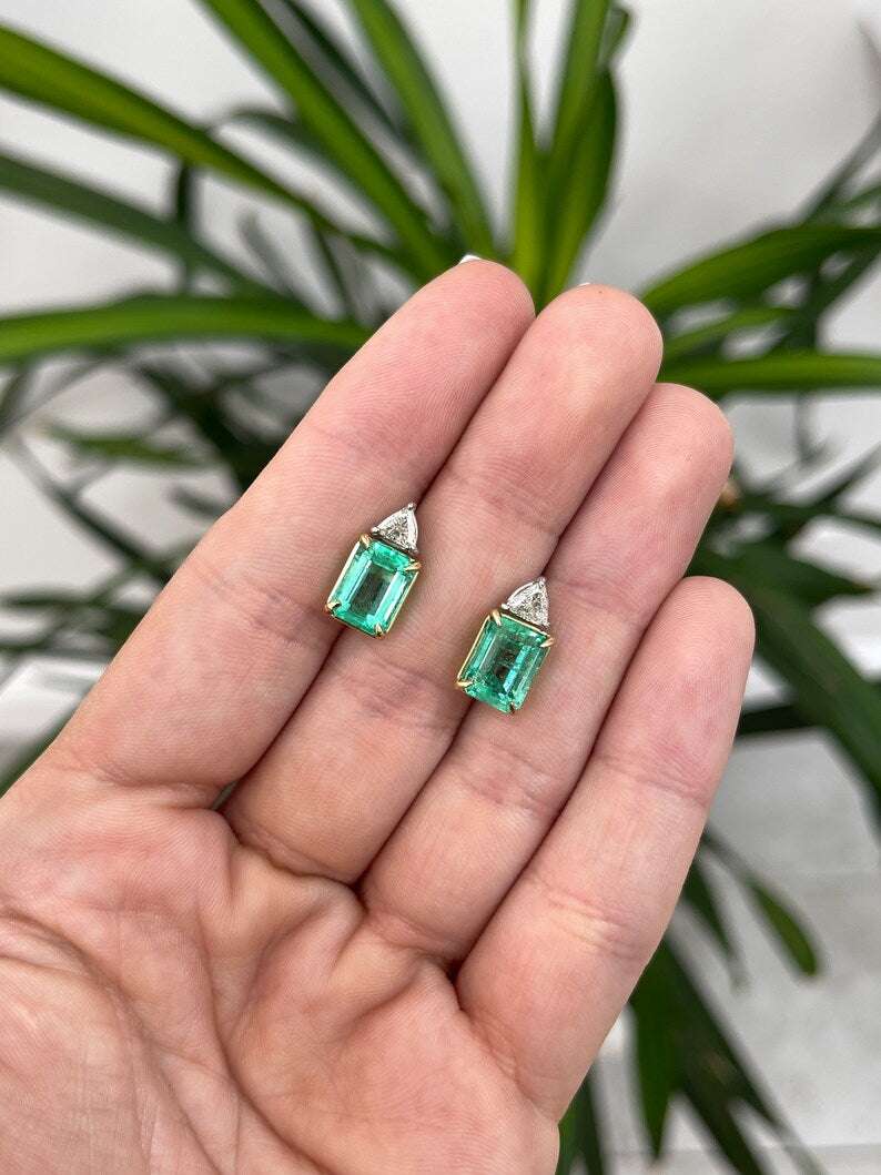 Colombian Emerald brand two-stone stud earrings featuring 6.73tcw platinum with Colombian emerald and diamond trillion accents