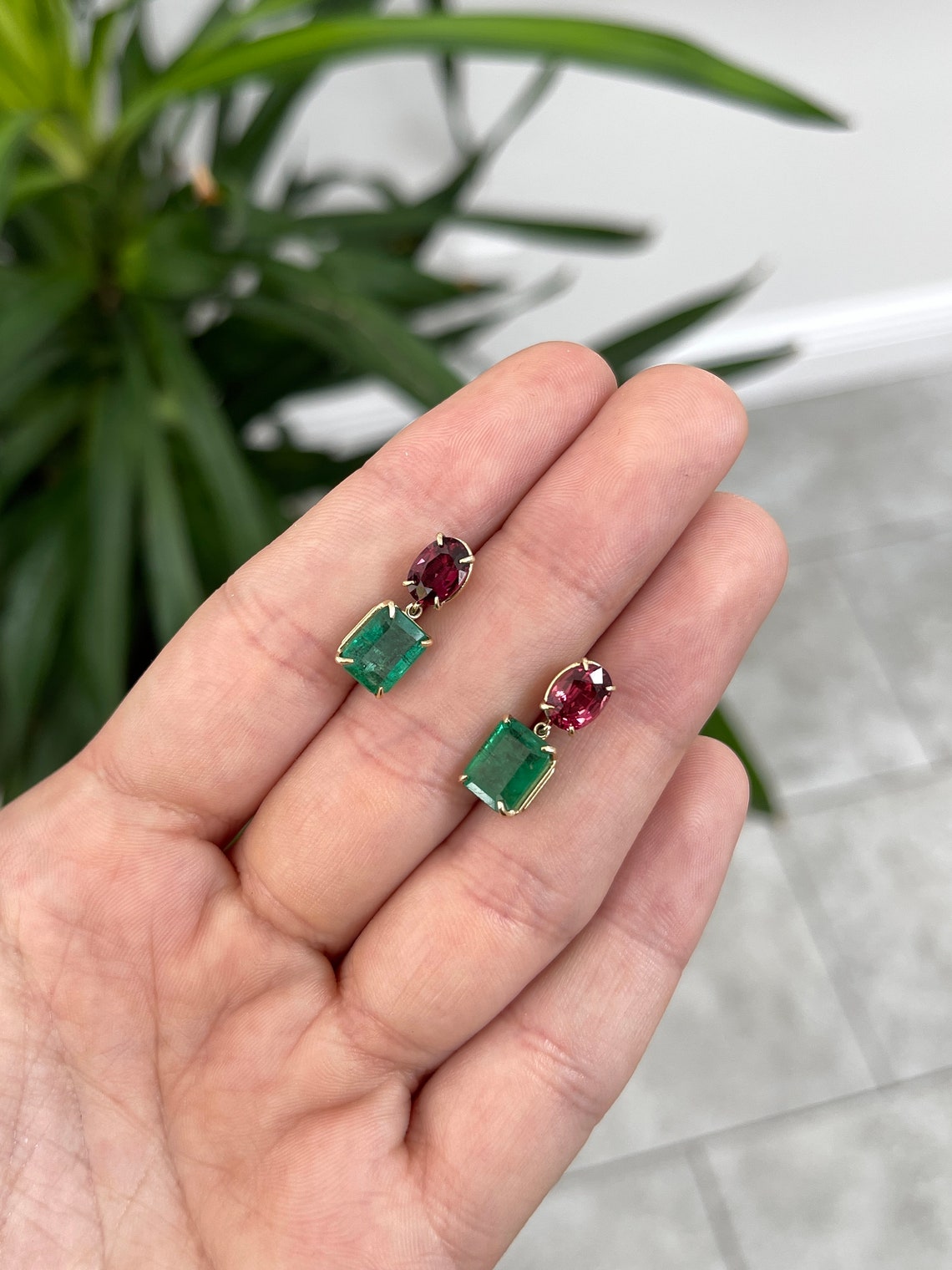 14K gold dangle earrings featuring natural emerald and oval-cut spinel gemstones, showcasing vibrant green and deep purple hues.