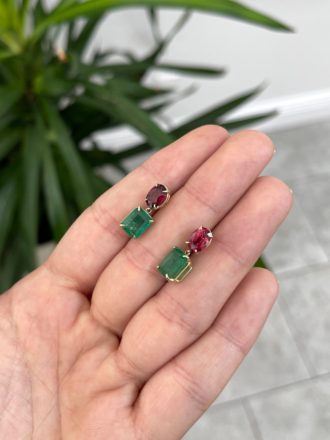 14K gold dangle earrings with 7.09 carats of natural emerald and oval cut spinel, featuring Colombian Emerald branding.