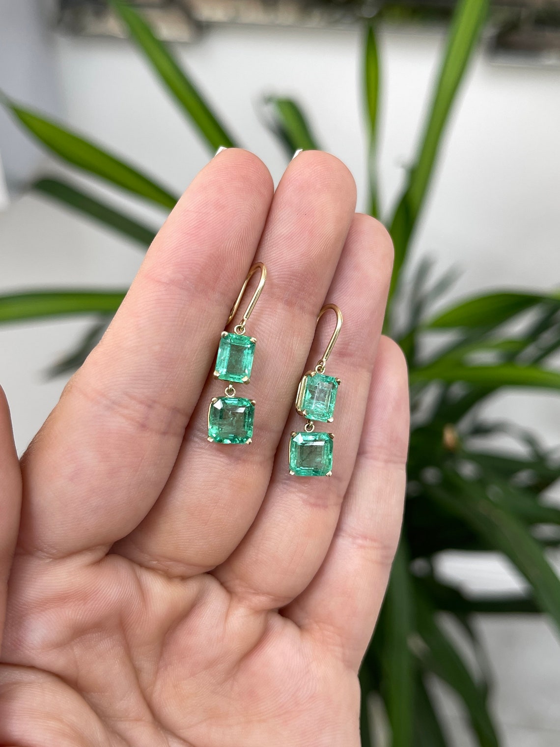 Colombian Emerald 14K gold dangle earrings featuring natural emeralds with Asscher cut stones on hook wire.