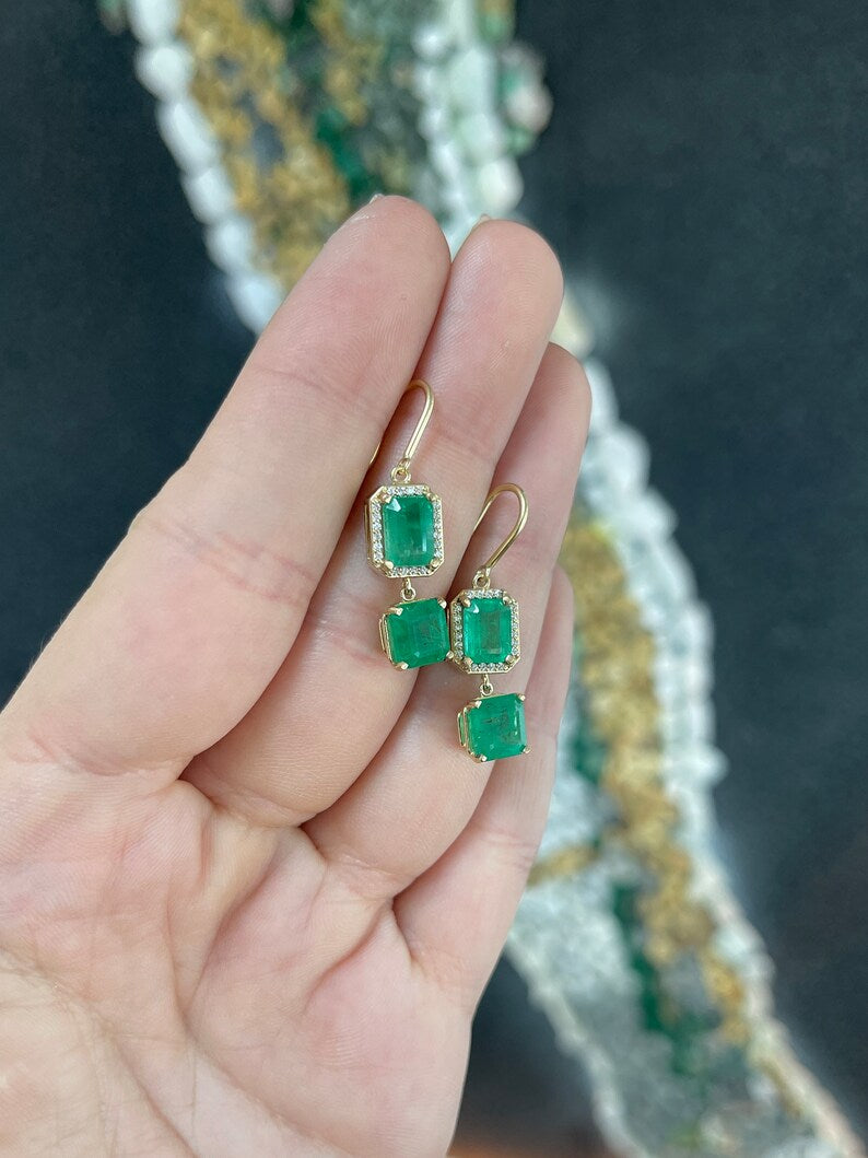 14K gold emerald and diamond halo dangle earrings featuring 7.39 carats of natural Colombian emeralds and sparkling diamonds.