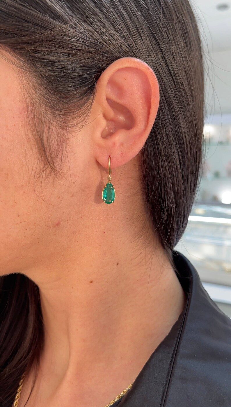 Colombian Emerald earrings with 5.0tcw dark green teardrop emerald dangles on gold hooks showcasing lush gemstone detail.
