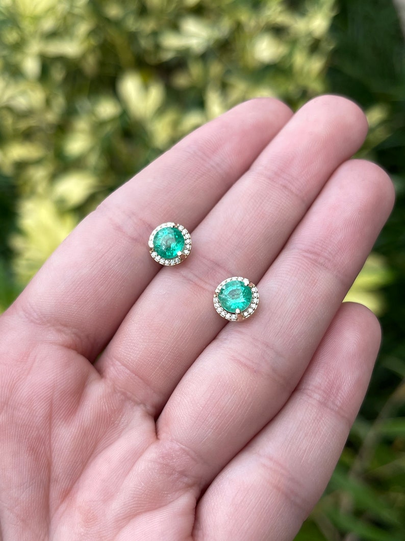 14K gold emerald and diamond halo stud earrings, 8.5mm round shape, Colombian Emerald brand, featuring sparkling gemstones.