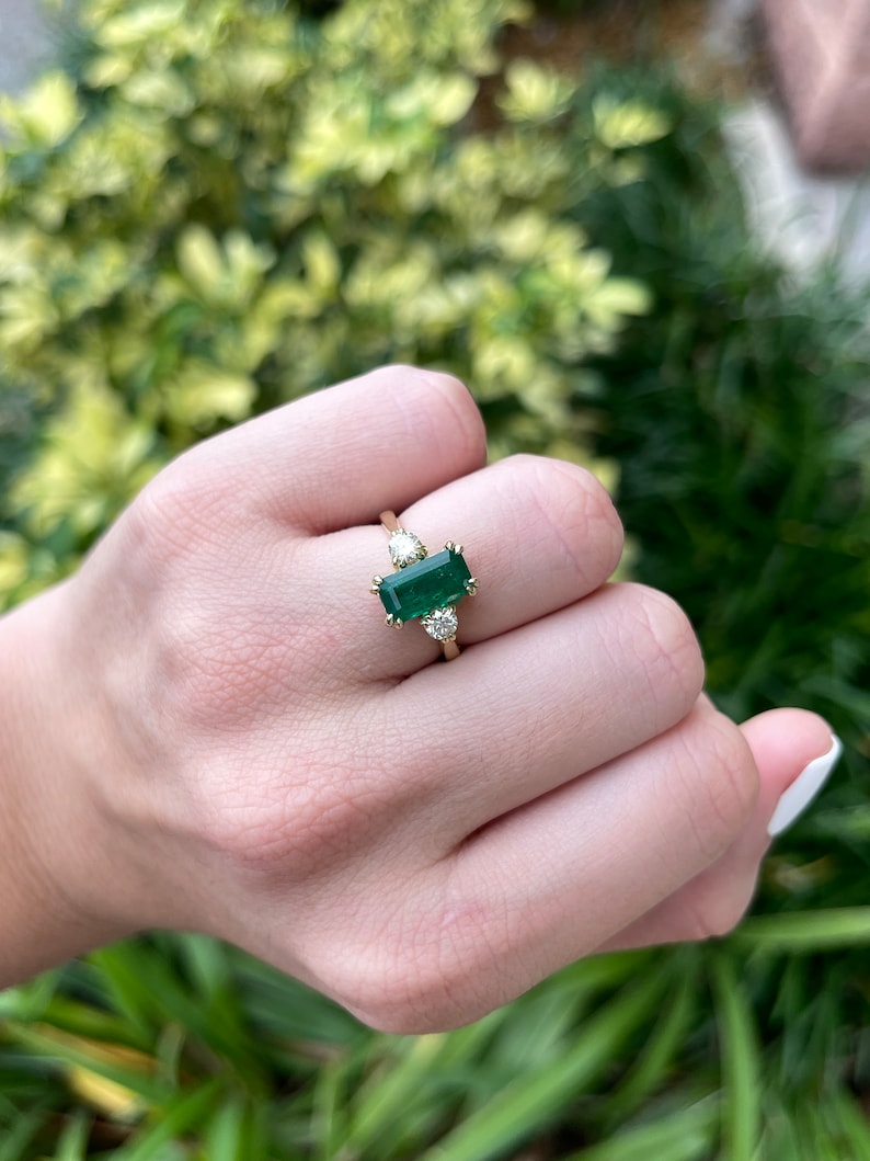 18K natural emerald cut and round diamond three-stone engagement ring with deep dark alpine green Colombian emeralds and sparkling diamonds