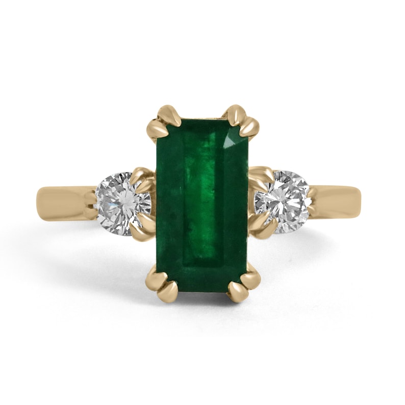 Colombian Emerald 18K gold three-stone engagement ring with deep dark alpine green emerald cut and round diamonds.
