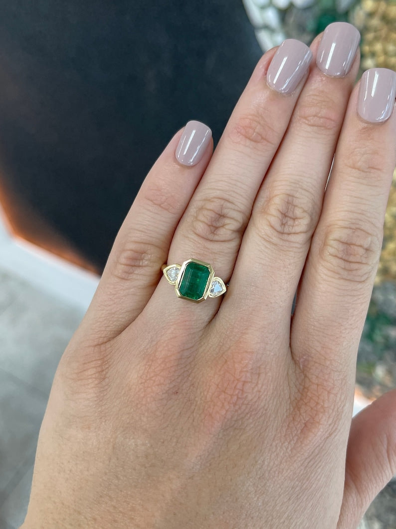Colombian Emerald 18K yellow gold engagement ring featuring a heart-cut diamond and emerald in a three-stone design.