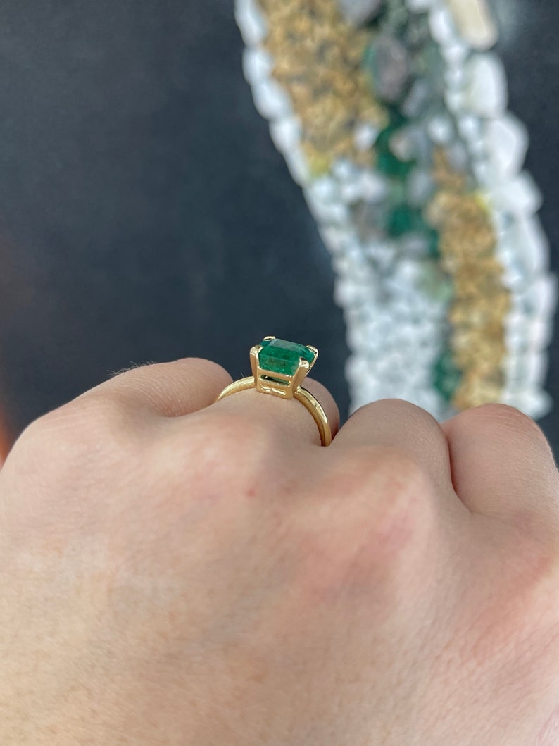 18K yellow gold emerald cut solitaire engagement ring with four prongs and half bezel setting, featuring a 4.10 carat Colombian emerald.