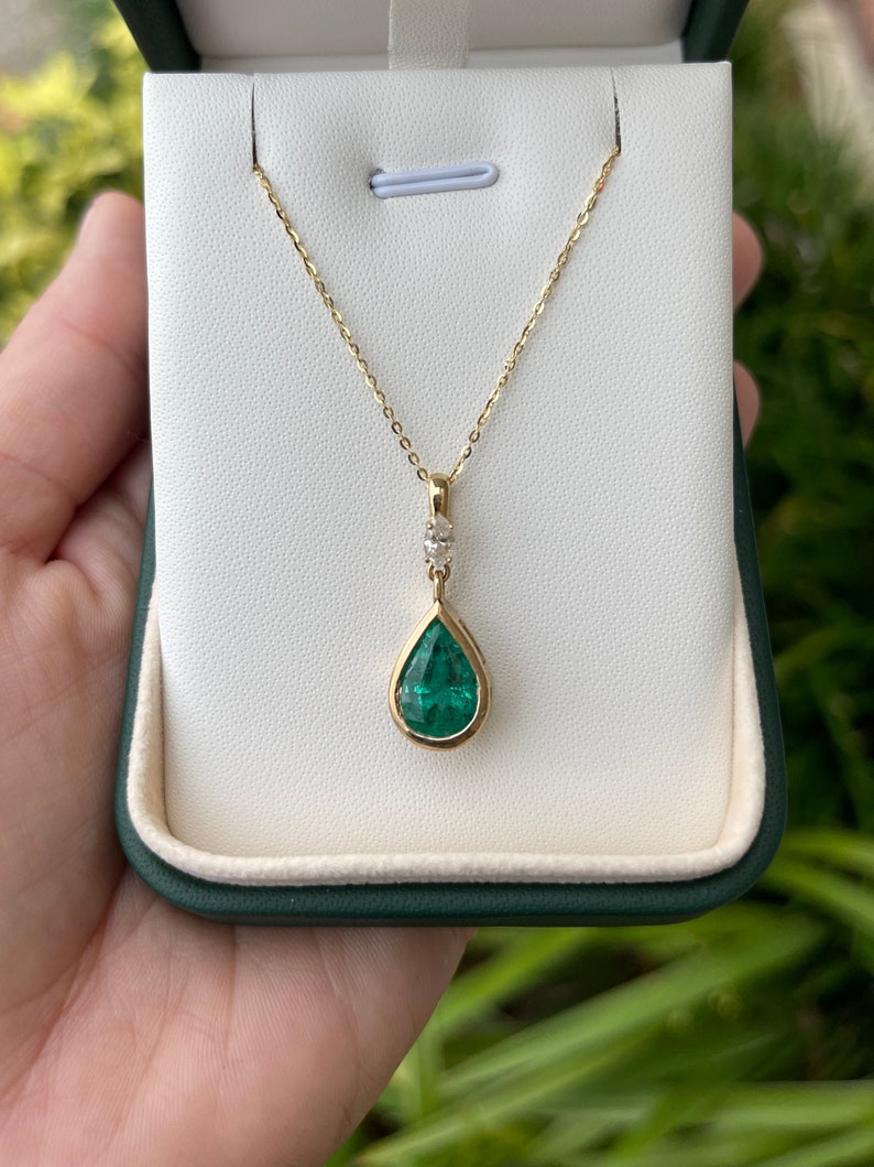 Colombian Emerald teardrop pendant necklace with bezel-set pear-cut emerald and marquise diamond bail in 14K gold.