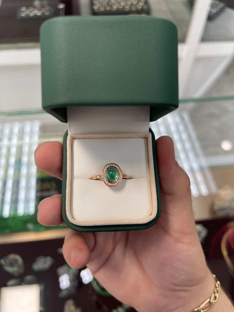 Colombian Emerald ladies ring with oval cabochon emerald, diamond pave halo, and contemporary design.