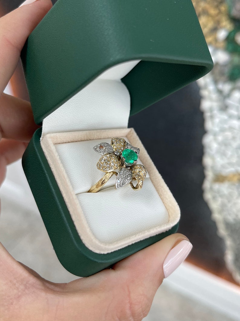 Ladies emerald and diamond cluster cocktail ring with floral design, 14K gold, featuring round cut emeralds and leaf accents.