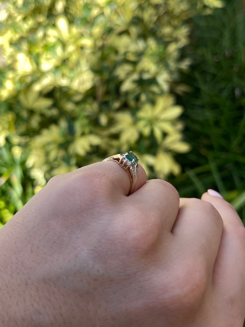 Ladies emerald ring featuring a 1.81tcw dark green oval cut emerald with diamond accents in 14K gold, natural and lustrous.