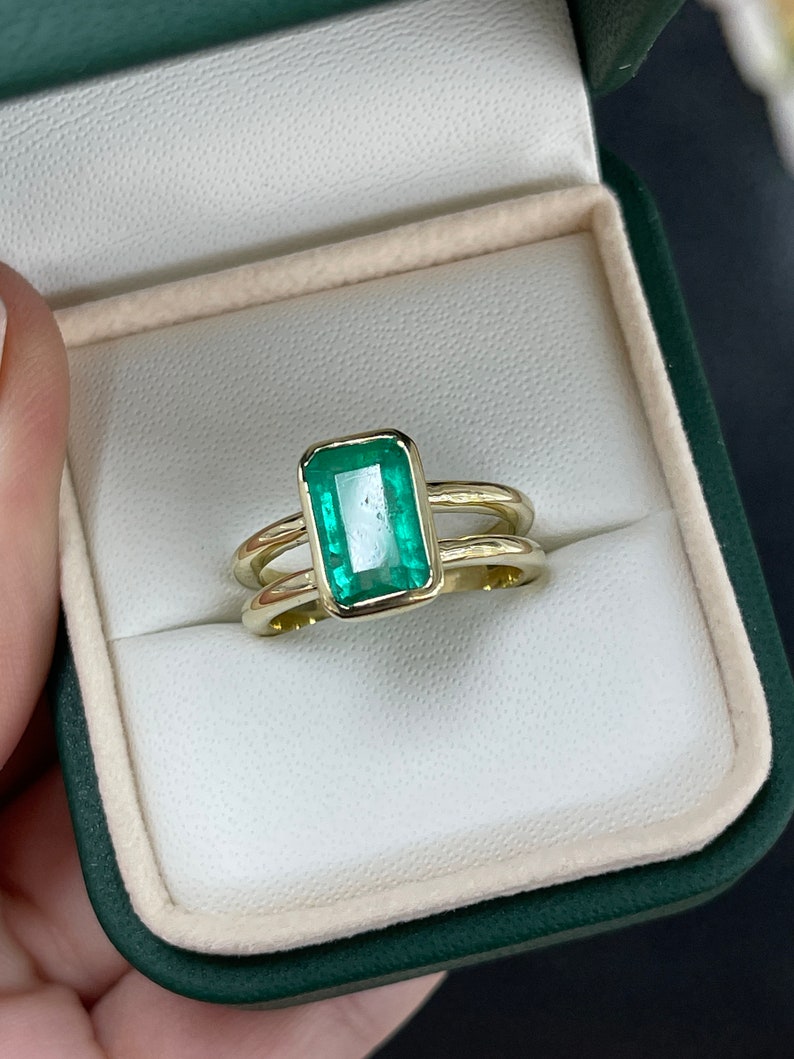 14K gold ladies emerald ring with a vivid green 2.05ct emerald cut solitaire and split shank design, right hand jewelry.