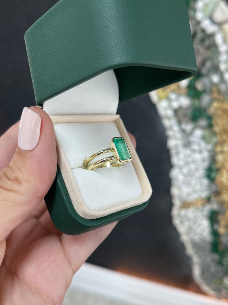 Colombian Emerald ladies ring with 2.05ct vivid green emerald cut gemstone and split shank 14K gold solitaire design.