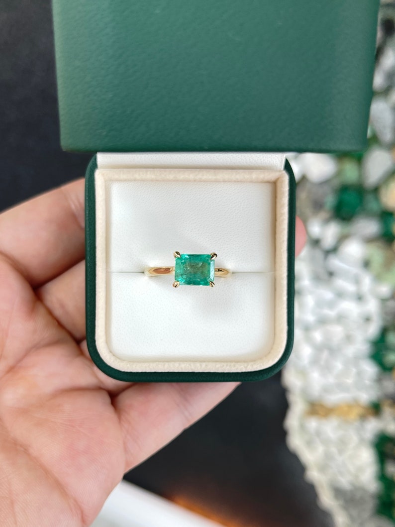 14K gold east-to-west emerald solitaire ring for ladies featuring a 2.10 carat Colombian emerald on a simple band.