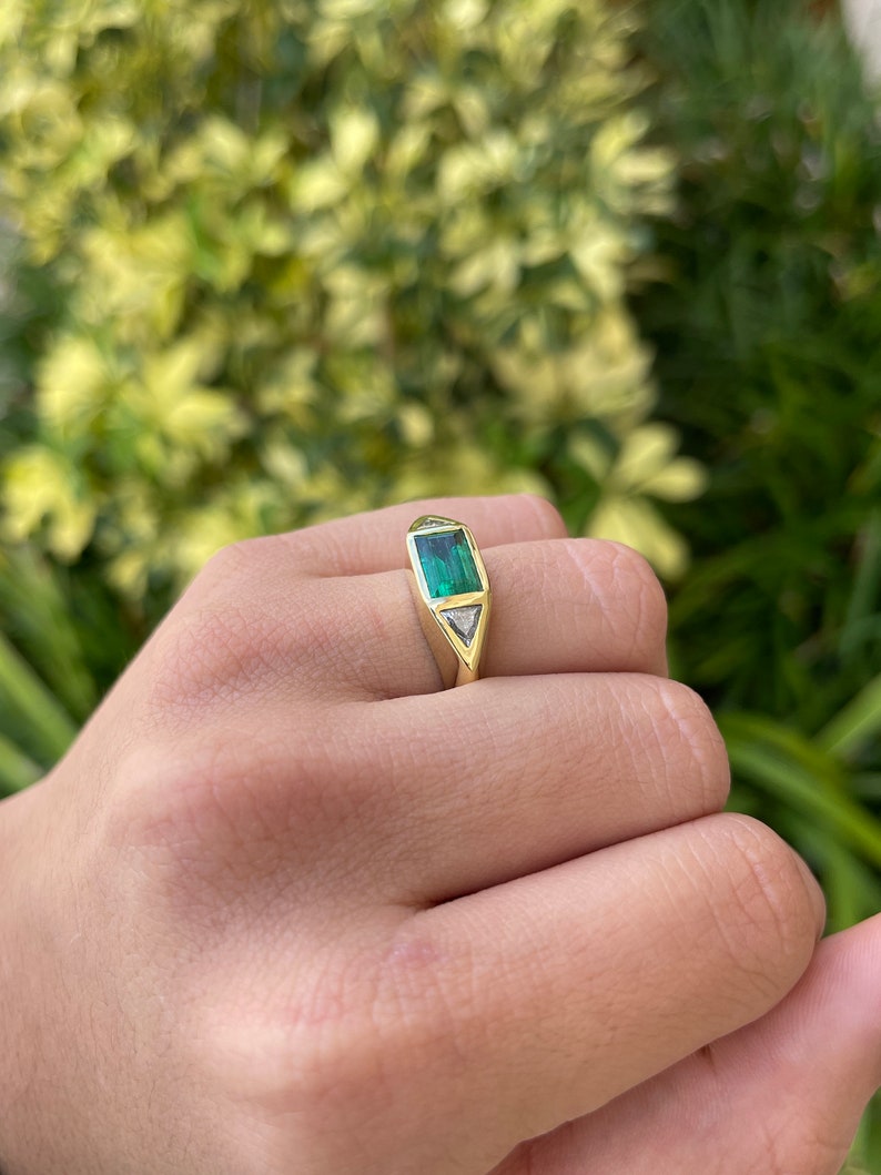 Ladies 18K Colombian Emerald and diamond gypsy ring featuring three stone baguette and trillion cut diamonds, vivid green emeralds.